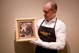 Sotheby's manager holds William Dobell portrait which sold for close to $1 million.