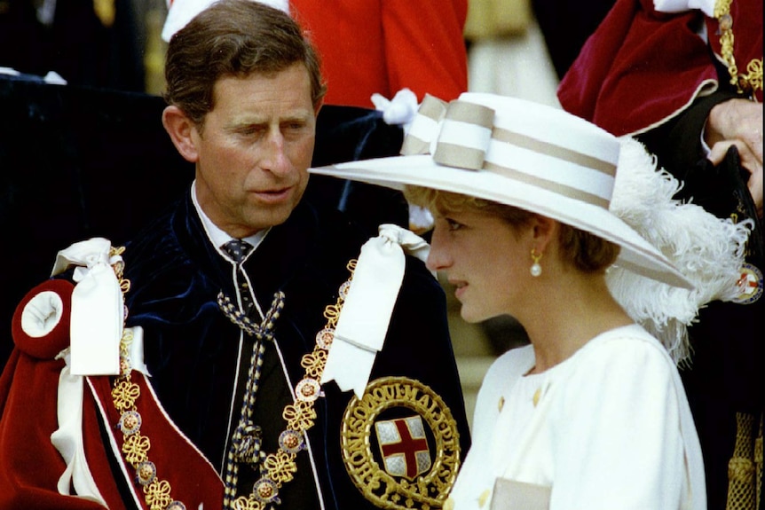 Prince Charles dressed in a military uniform looks towards Princess Diana dressed in white.