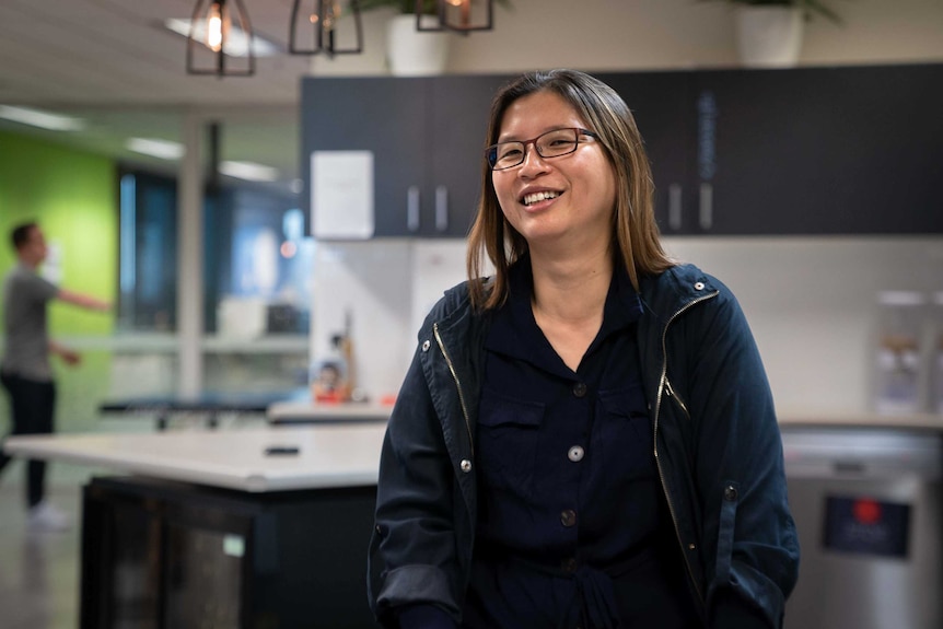 Wenee Yap stands in a work room laughing.