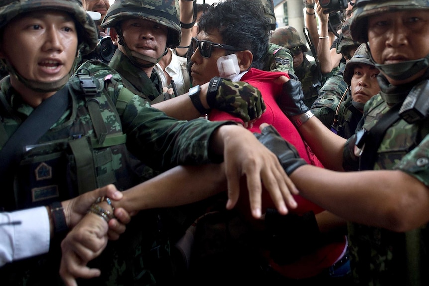 Thai soldiers take away an alleged Red-Shirt protester ahead of a planned gathering in Bangkok.