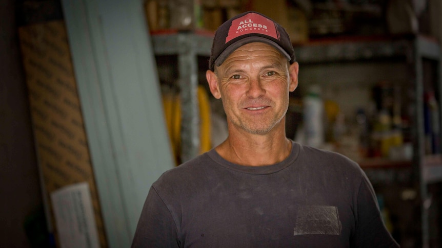 A middle-aged man in a baseball cap looking at the camera