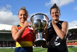 Carlton Blues captain Bri Davey and Adelaide Crows co-captain Erin Phillips stand holding the AFLW trophy at Adelaide Oval