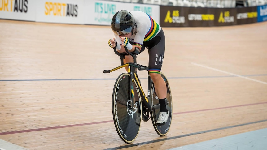 An action shot of a woman cycling in an indoor arena