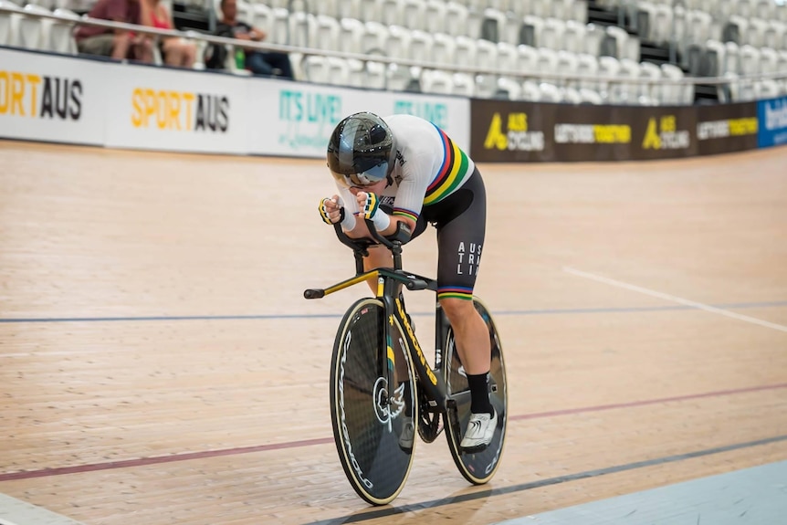 An action shot of a woman cycling in an indoor arena