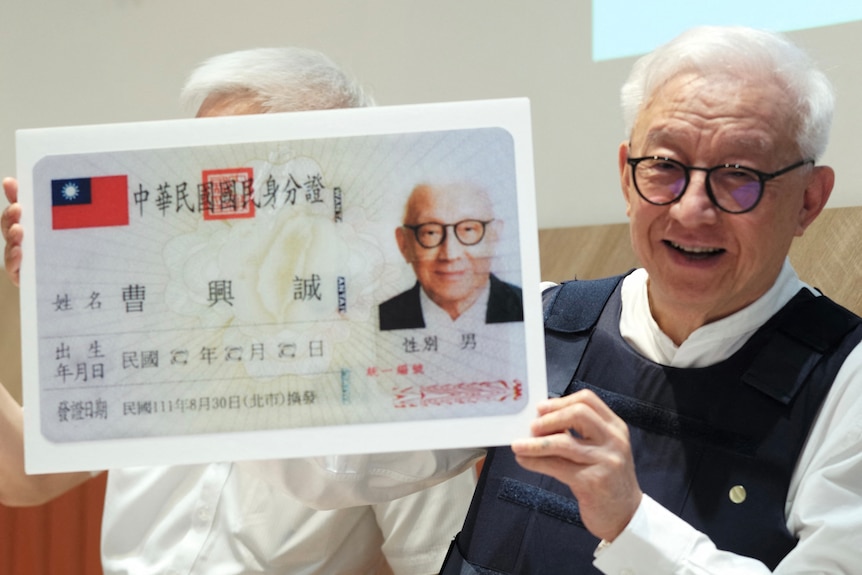 Robert Tsao displays an enlarged copy of his identity card during a press conference