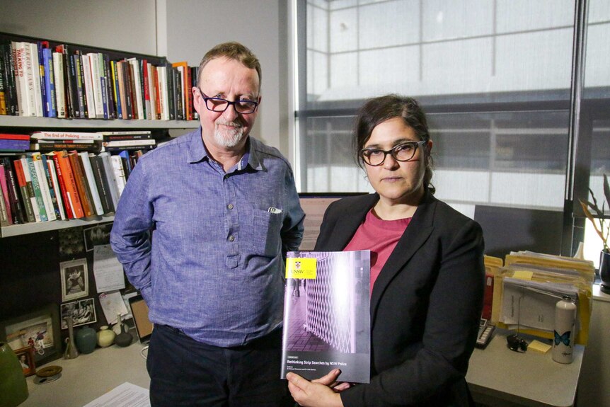 Dr Vicki Senta holds her report at UNSW, she is wearing glasses and is standing next to a tall white man, another researcher.