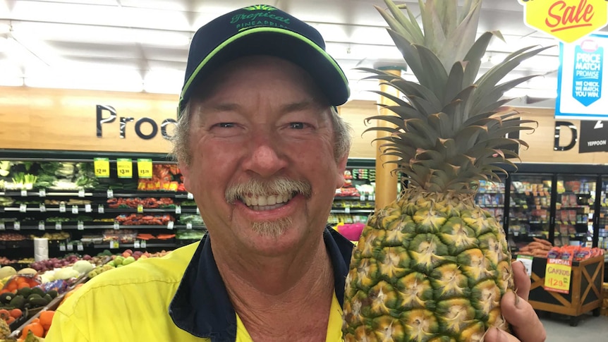 Yeppoon pineapple farmer Peter Sherriff holds up a pineapple in a local supermarket fruit and vegetable department