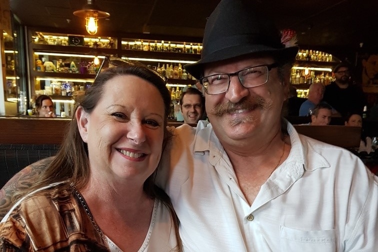 A woman and a man with arms around each other in a restaurant