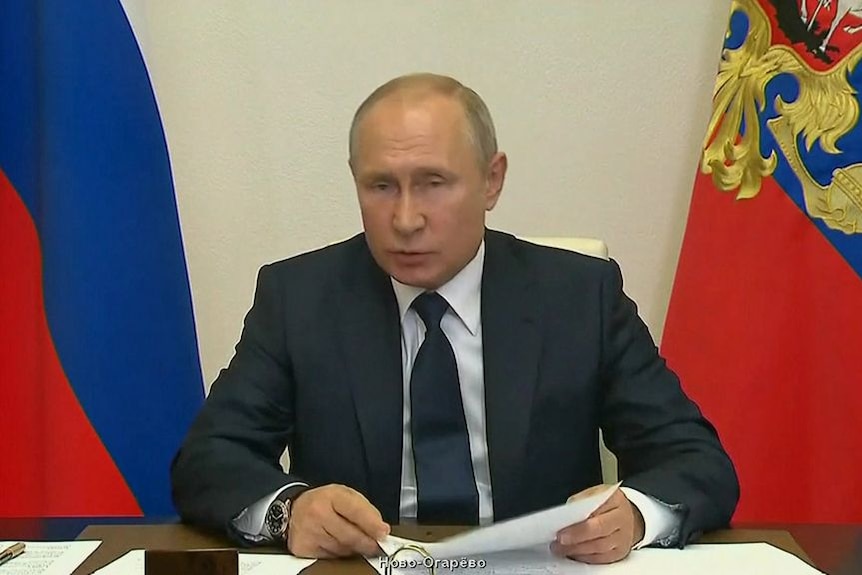 A man sits in front of the Russian flag