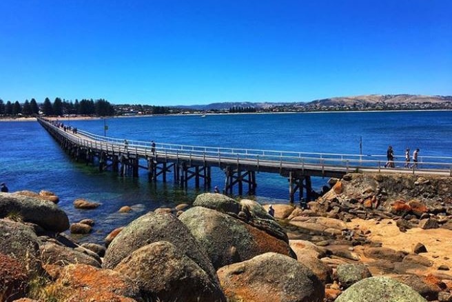 A jetty across the sea with rocks in the foreground