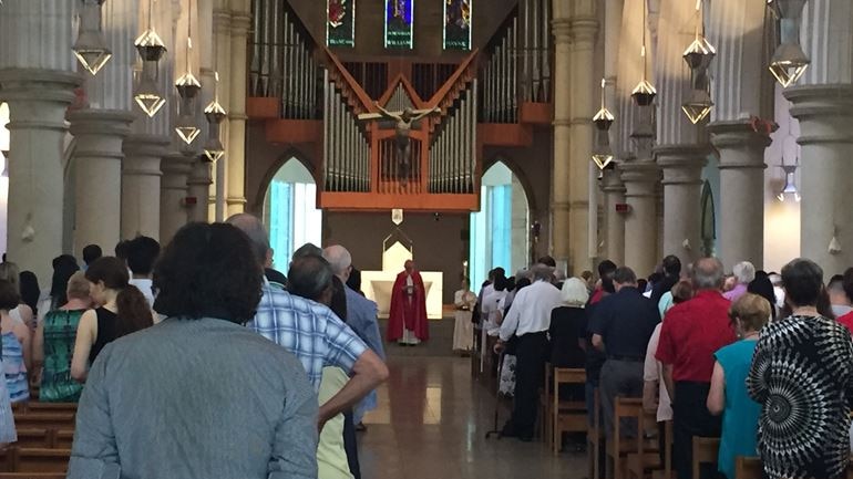 A photo is taken from the back of a church showing the backs of the crowd of people who attended the service.