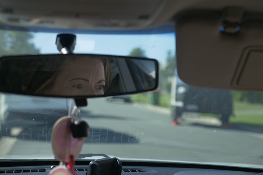 A woman's eyes seen in a rear vision mirror as she looks ahead at the road. 