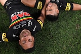 Penrith Panthers players Apisai Koroisau and Stephen Crichton lie on the grass field after the 2021 NRL grand final.