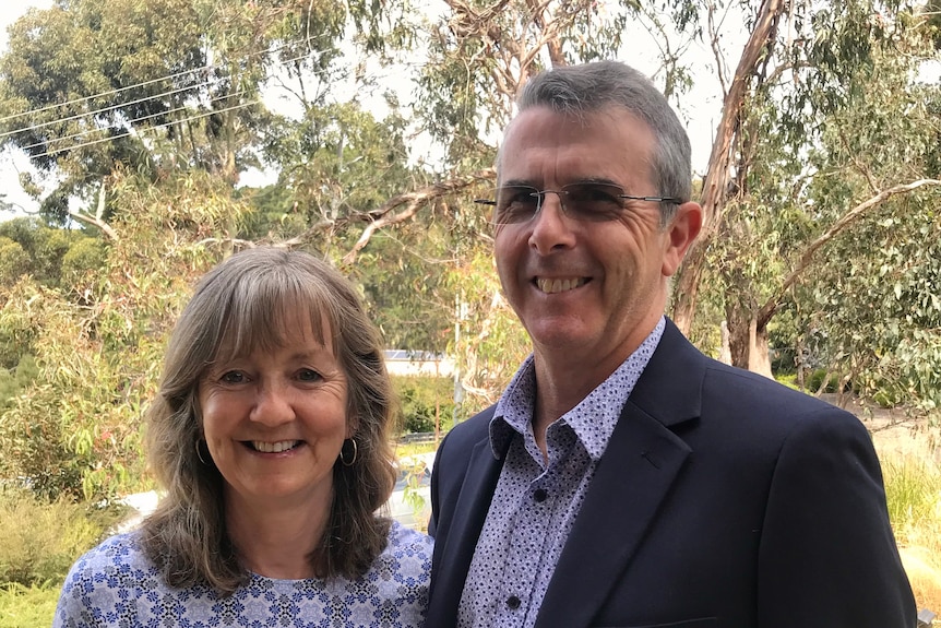 Woman with brown shoulder length hair standing with man with greying hair.