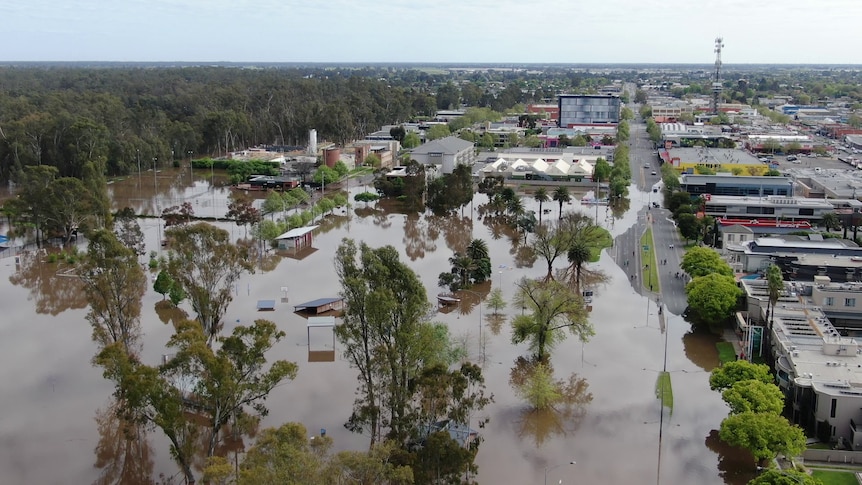 An aerial shot of a town about to be inundated by murky floodwater.