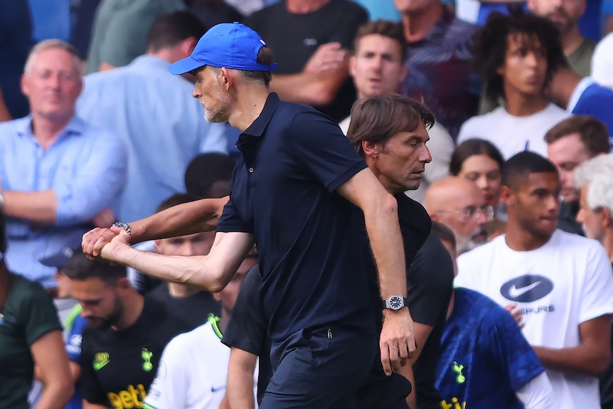 Chelsea manager Thomas Tuchel holds onto Tottenham manager Antonio Conte's hand as they pass each other.