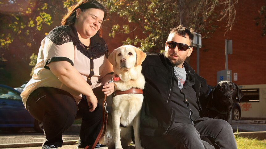 Sam and Danny Noonan sit outside with their dogs, a white and brown labrador.