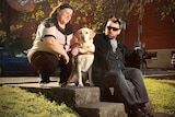 Sam and Danny Noonan sit outside with their dogs, a white and brown labrador.