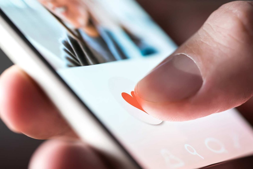 A close-up of a hand pressing the heart icon on a social media app on a smartphone.