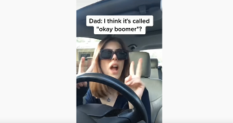 A woman does air quotes while sitting in the driver's seat of a car, with the subtitles "Dad: I think it's called 'ok boomer'"