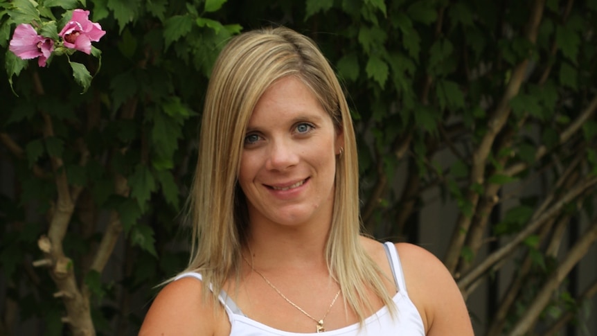 Tara Costigan in front of a tree with flowers on it.