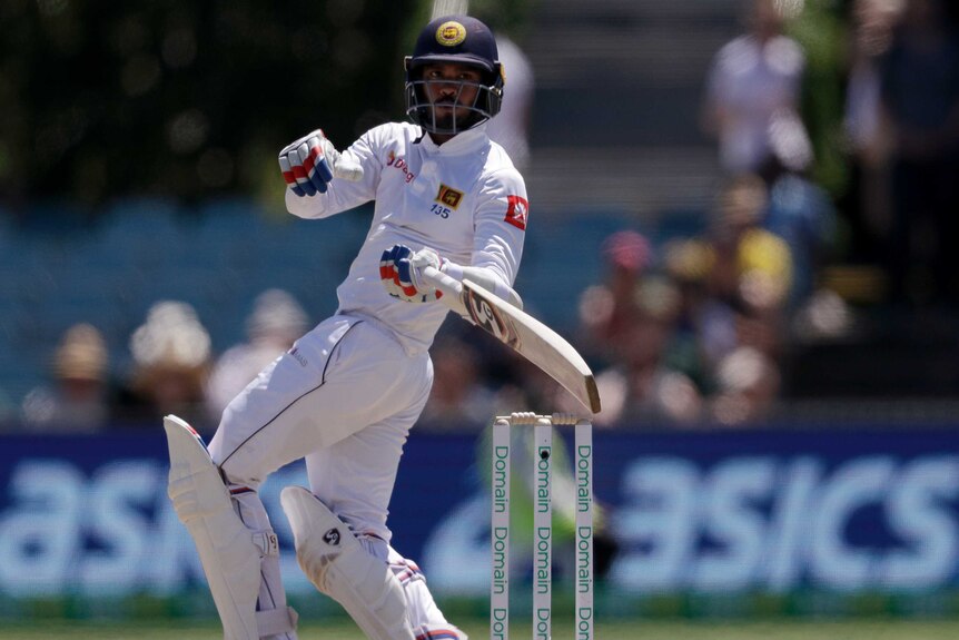 A batsman holds his bat inches above the bails looking behind him