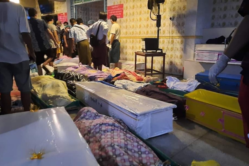 People line up with bodies in coffins at a Yangon crematorium