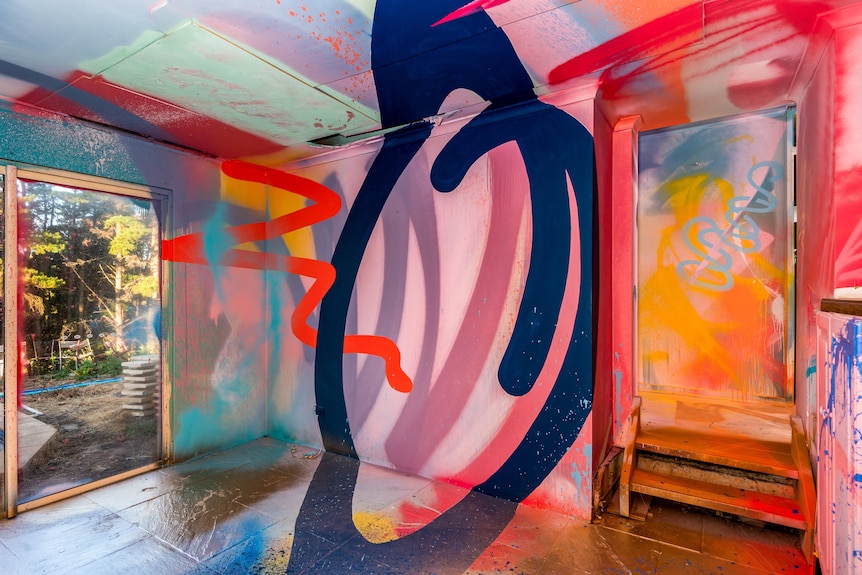 A large blue swirl is painted over the floor wall and ceiling of a brightly coloured back room