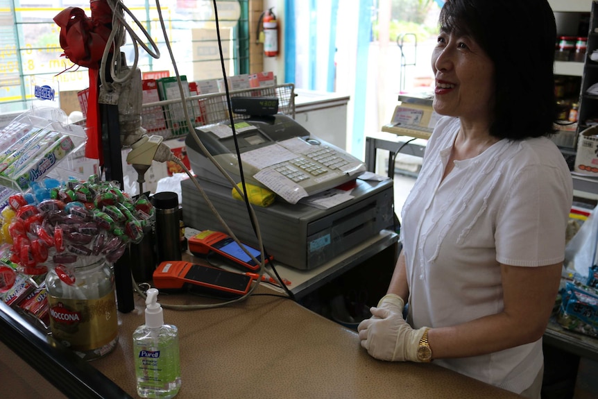 Vincent Liu's wife gets a receipt for a customer in her grocery shop.