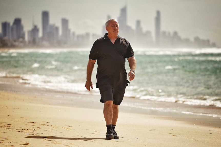 Glen Day walks along a beach.