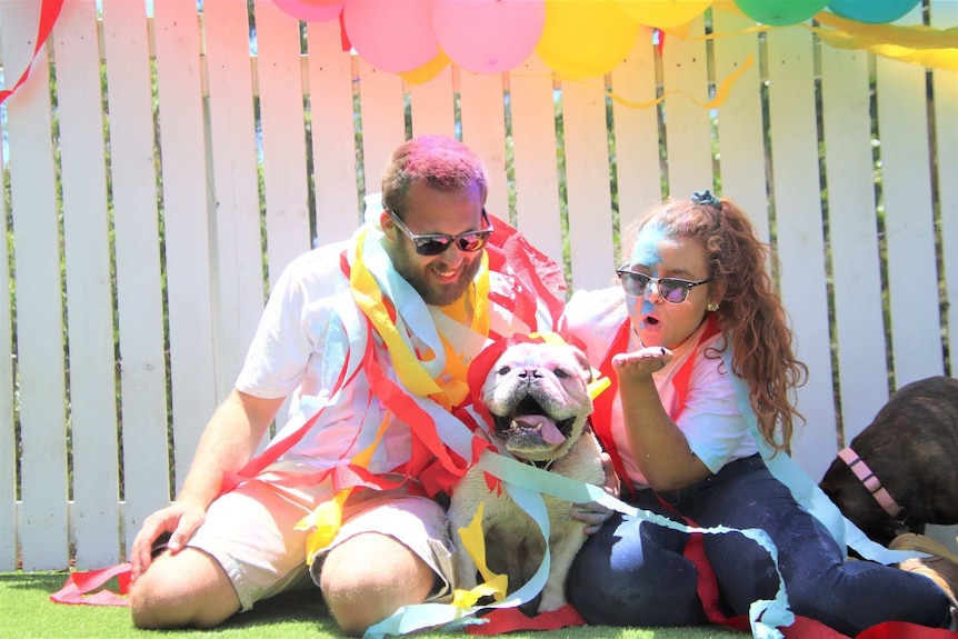 two people with balloons near a dog