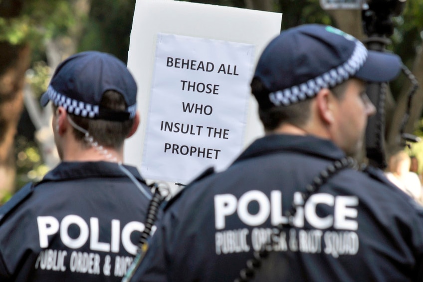 Protester holds placard calling for beheading