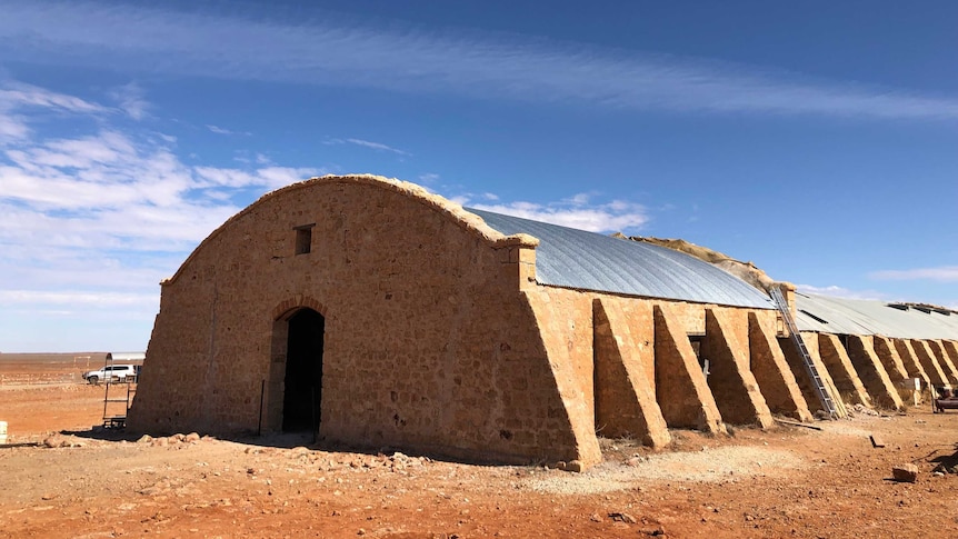 A stone building with a domed roof. One part of the roof is much newer than the other.