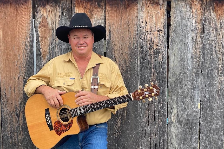 A man with a guitar and cowboy hat.