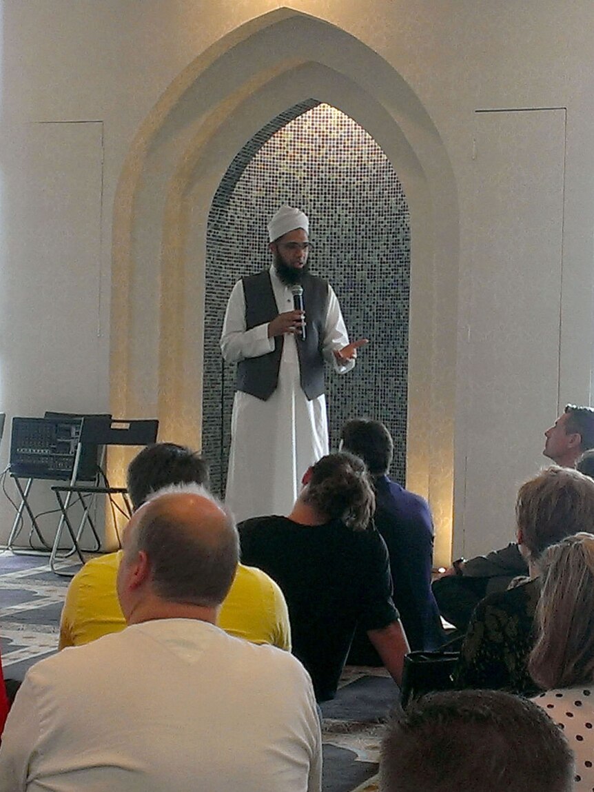 An iman speaks to visitors in a mosque