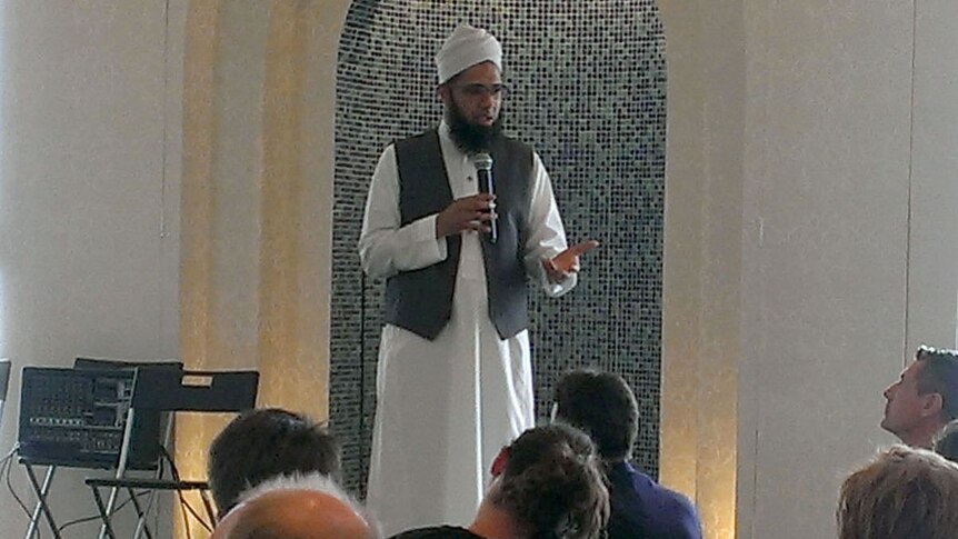 An iman speaks to visitors in a mosque