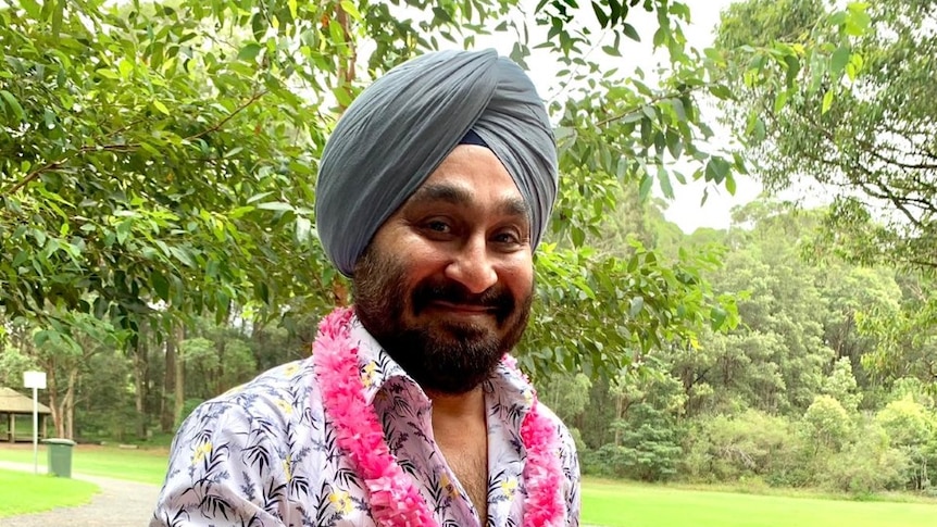 Manmohan Bedi smiles at the camera and holds out a coke can.