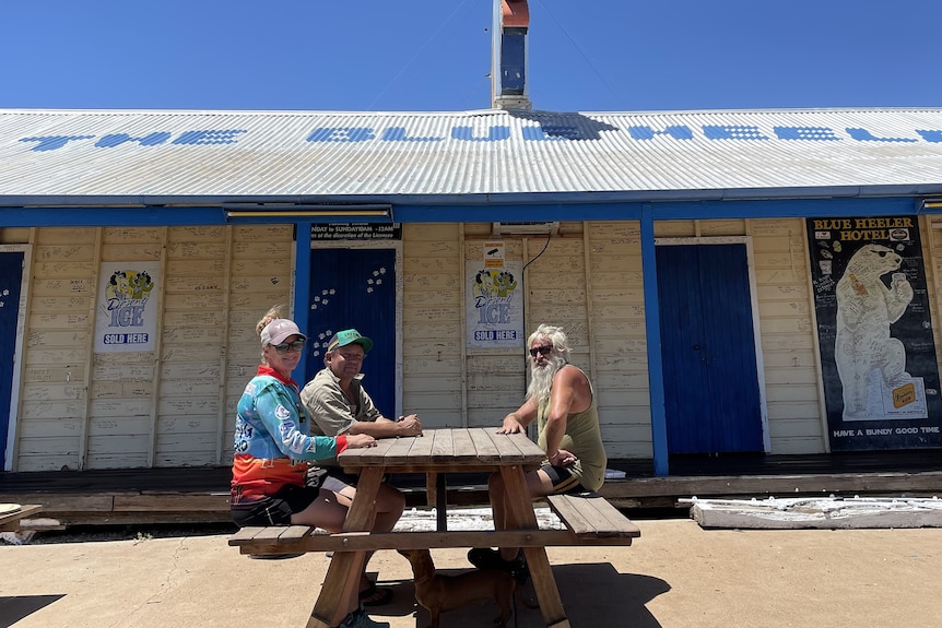 three people sit at table outside pub in outback Queensland