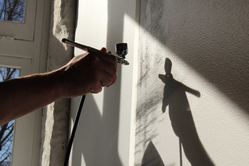 Josh Foley painting the wall in a Salamanca gallery in Hobart, 13 August 2014.