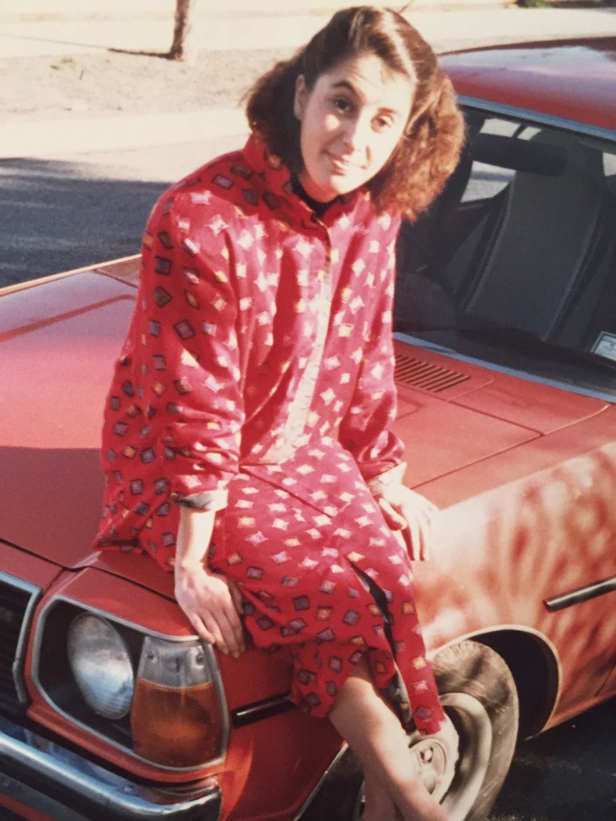 An old photo of Amanda Pepe sitting on a car bonnet