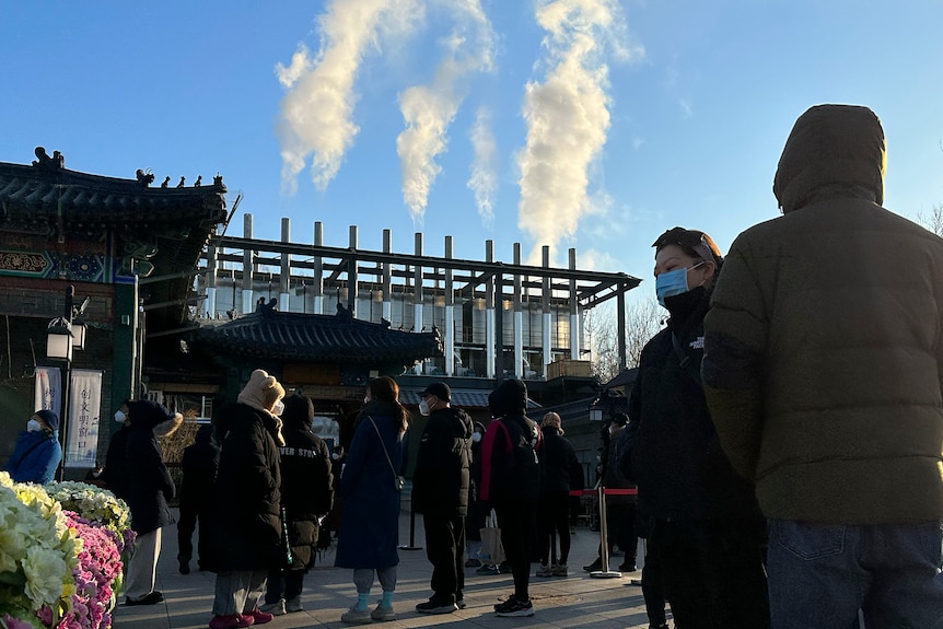 Mourners stand outside crematorium as white smoke pour out of chimneys used for cremation in Beijing.