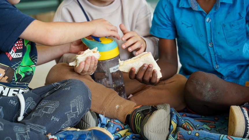 Young children eating sandwhiches.