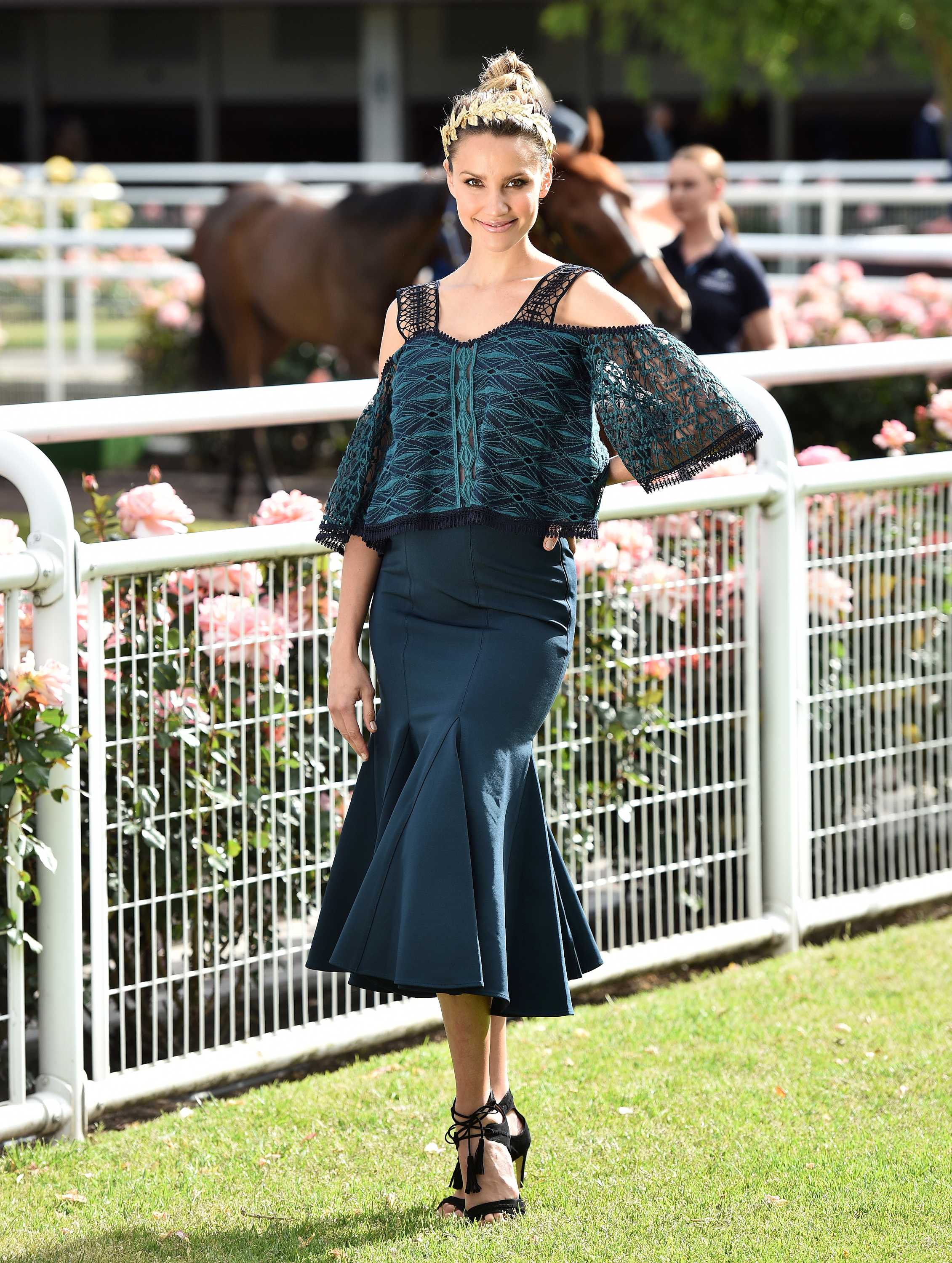Woman wears teal skirt and top with gold headband