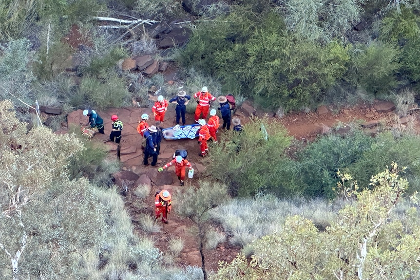 Aerial shot of a crew of SES workers surrounding a woman on a stretcher