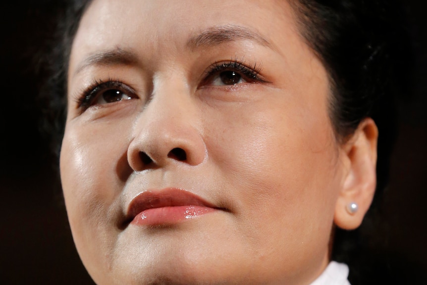 Close-up of Peng Liyuan's face.  She brushed her hair while wearing pearl earrings