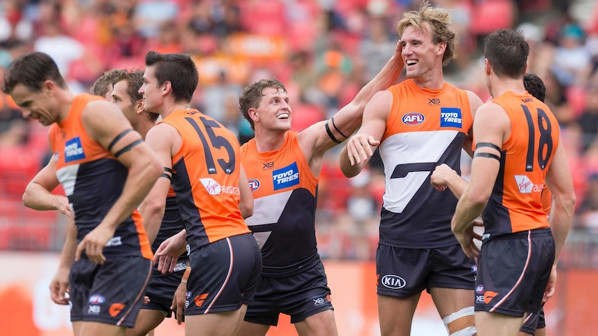 Lachie Keefe's much shorter teammates reach to rub him on the head after he kicked a goal.