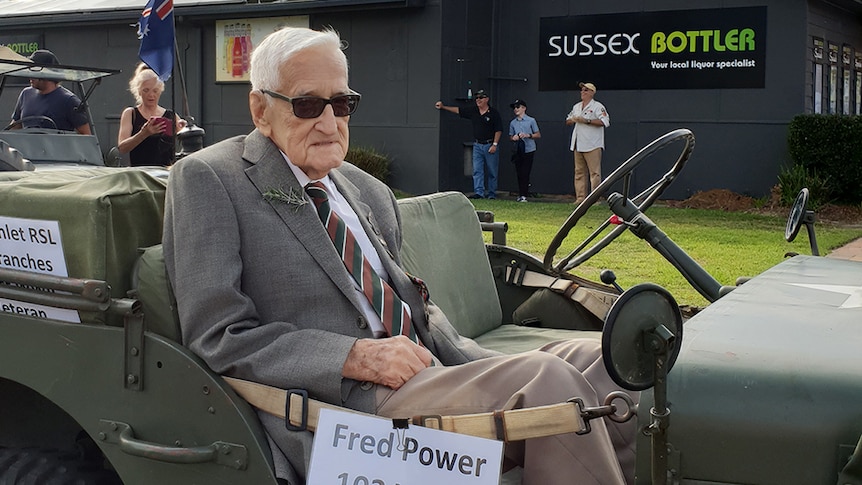 Fred Power rides in a vintage military vehicle with an Australian flag in an Anzac Day parade.