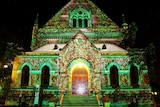 A building lit up with decorative projections illustrating a forest