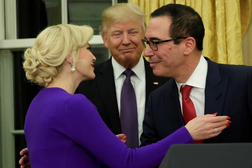 Donald Trump looks as Steve Mnuchin is congratulated by Louise Linton.