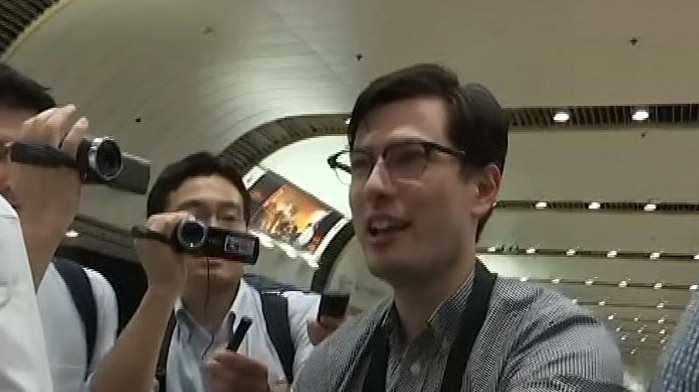 Australian student Alek Sigley walks past media  in a Beijing airport after he was released from detention in North Korea.